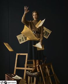 a woman standing on top of a pile of junk with her hands in the air