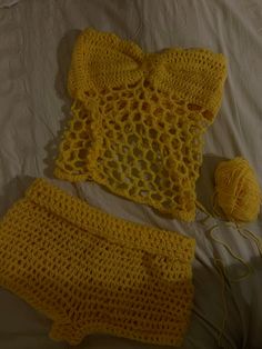 a crocheted yellow outfit and ball of yarn