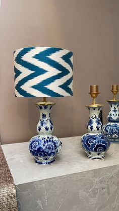 three blue and white vases sitting on top of a table next to a lamp