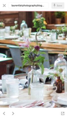 an image of a table setting with flowers in vases and plates on the table