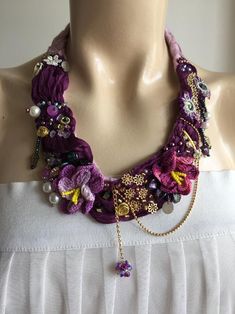 a woman wearing a purple necklace on top of a mannequin