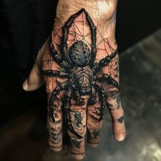 a man's hand with a spider tattoo on it and his hands are covered in black ink