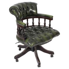 a green leather office chair sitting on top of a wooden desk