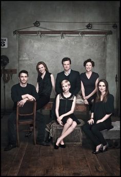 a group of people sitting next to each other on top of a wooden floor in front of a wall