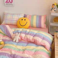 a smiley face pillow sitting on top of a bed next to a stuffed animal toy