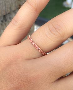 a woman's hand with a pink diamond ring on her left hand and the other hand holding an engagement band