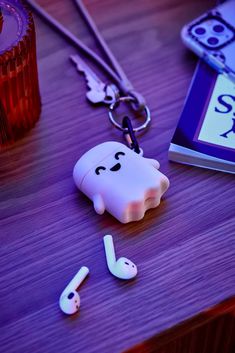 there is a keychain with a ghost on it next to an mp3 player