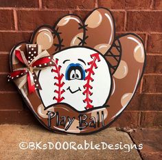 a sign with a baseball glove on it that says play ball and has a bow