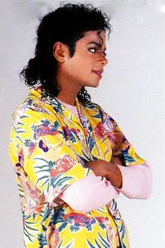 a woman with her arms crossed wearing a yellow floral shirt and pink elbow warmers