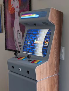 a video game machine sitting on top of a wooden table next to a wall with pictures above it