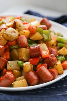 a white plate filled with cooked vegetables on top of a blue table cloth next to a fork