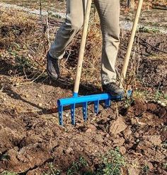 a man is digging in the ground with two shovels and a blue plastic fork