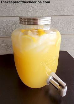 a mason jar filled with lemonade sitting on top of a wooden table next to a metal faucet