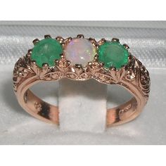 *This gorgeous trilogy ring is made from Solid 375 9ct 9K Rose Gold with Natural Semi-precious Opal and Emeralds.This ring has been completely made here in England from Solid 9ct Gold and is set with three Magnificent Gemstones. A Center Opal and Two Emeralds, equally sized measuring 4.5mm (0.18"), all individually chosen and hand set in this Substantial Ornate Antique / Victorian style setting which boasts a marvelous Foliage Scroll / Art Nouveau carving on the shoulders.PLEASE MAKE SURE YOU ST Emerald Three-stone Birthstone Ring, Three-stone Emerald Birthstone Ring, Three Stone Emerald Birthstone Ring, Unique Three Stone Rings For Anniversary, Unique Three Stone Anniversary Rings, Three Stone Opal Ring For Anniversary, Rose Gold Three Stone Round Jewelry, Heirloom Three-stone Round Emerald Ring, Victorian Three Stone Round Jewelry