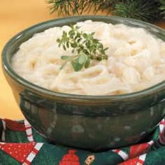 a bowl filled with mashed potatoes sitting on top of a table next to a christmas tree