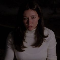 a woman in a white turtle neck sweater looking at the camera with an intense look on her face