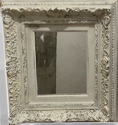 an old white frame with a mirror in it