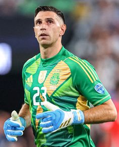 a soccer player wearing blue gloves and holding a ball