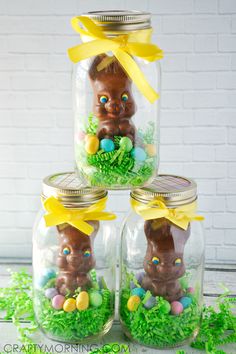 three glass jars filled with easter decorations