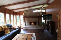 a living room filled with furniture and a flat screen tv mounted on a wall next to a fire place