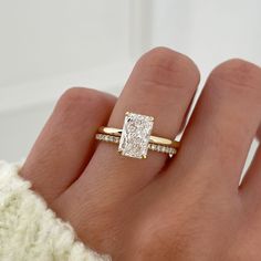 a woman's hand with a diamond ring on top of her finger and an engagement band