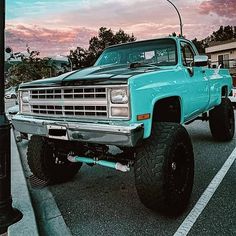 a blue truck parked in a parking lot next to a light pole and lamp post