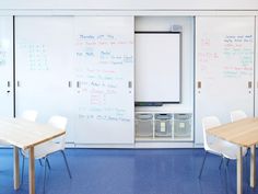 a room with several tables and whiteboards on the wall, including two chairs in front of them