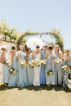 a group of women standing next to each other in front of an arch holding umbrellas