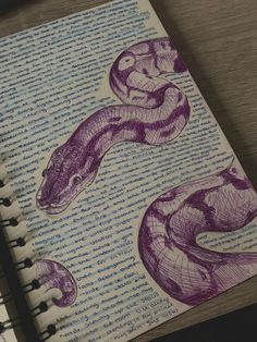 an open notebook with drawings of two snakes on it