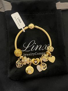 a gold bracelet with charms on it and a tag that says live jewelry comma