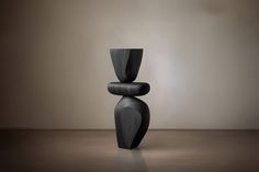 a tall black vase sitting on top of a wooden floor