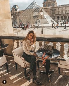 a woman sitting at a table in front of the pyramid