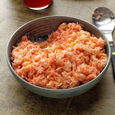 a bowl filled with food next to a fork and spoon on a table top,