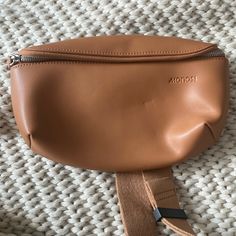 a brown leather pouch sitting on top of a white blanket