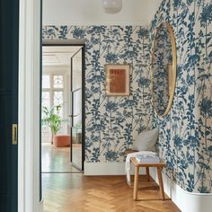 the hallway is decorated with blue and white wallpaper, along with an oval mirror