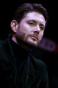 a close up of a person wearing a suit and tie with a black shirt on