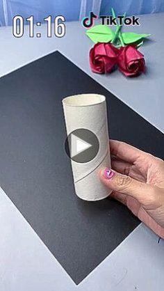 someone is holding a roll of toilet paper in front of a video screen with origami flowers on it