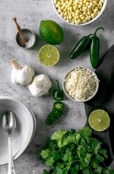 ingredients to make mexican corn salad laid out on a grey surface with limes and cilantro