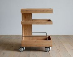 a wooden cart sitting on top of a hard wood floor next to a white wall