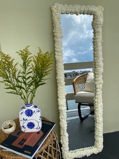 a mirror sitting on top of a table next to a vase