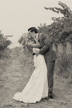 a bride and groom kissing in the middle of an apple orchard with their arms around each other