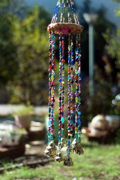 a wind chime with bells hanging from it's sides in the grass outside