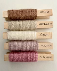 four skeins of yarn in different colors and sizes with names on each skewer