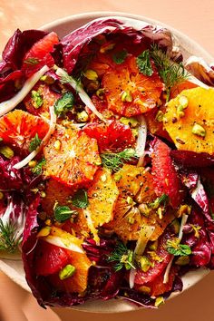 a salad with oranges, fennel and seeds in a white bowl on a table