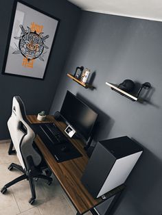 a computer desk with a monitor and keyboard on it in front of a gray wall