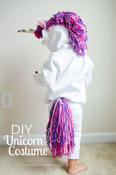 a child wearing a unicorn costume with pink and purple hair