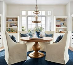 a dining room table with four chairs around it and built - in bookcases