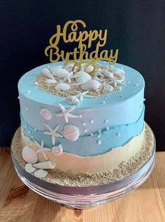 a blue and white birthday cake with seashells on it