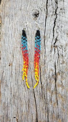 two pairs of colorful beads hanging from the side of a piece of wooden planks