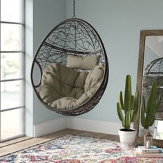 a hanging chair in the corner of a room next to a potted plant and mirror